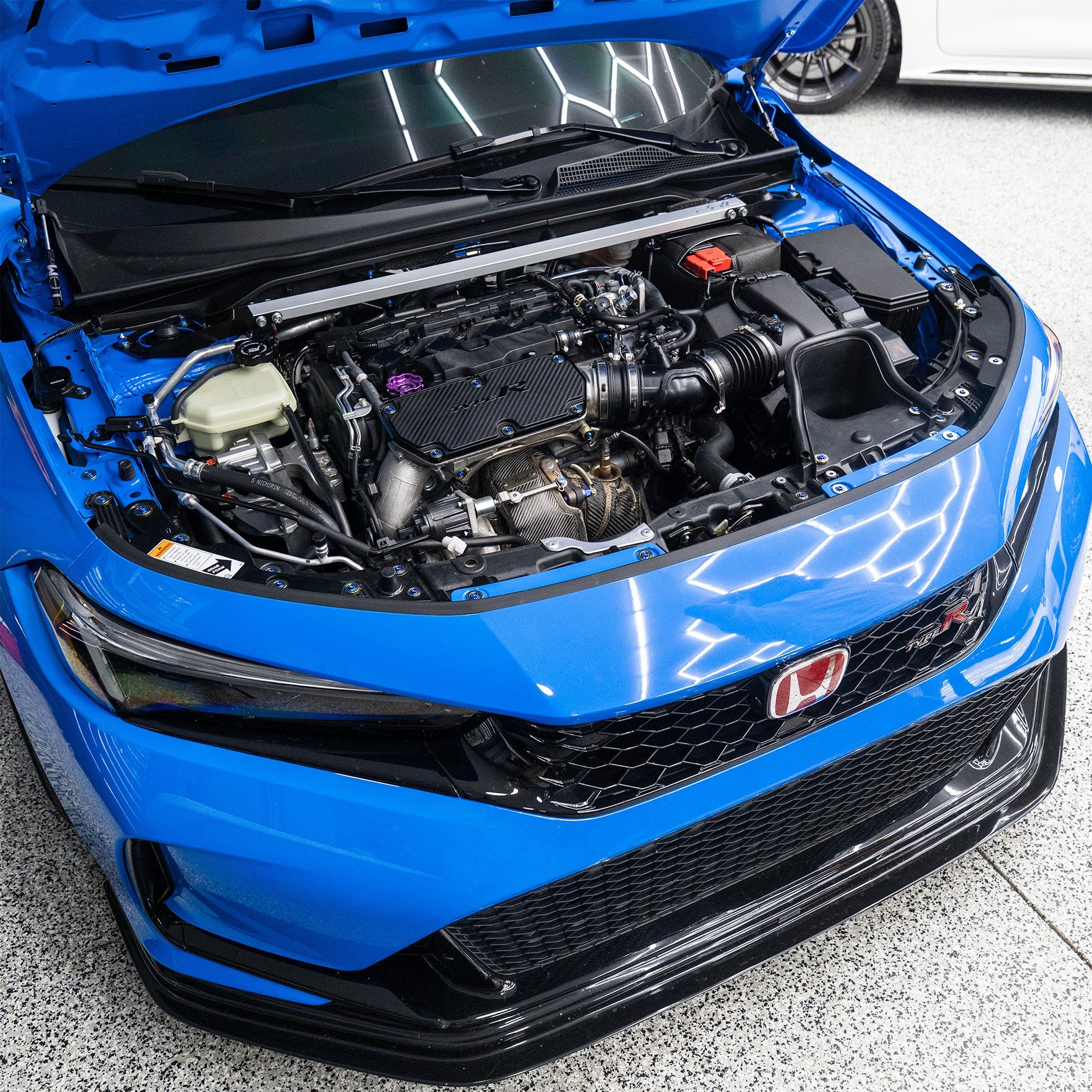 Blue car with open hood showing engine hardware kit.