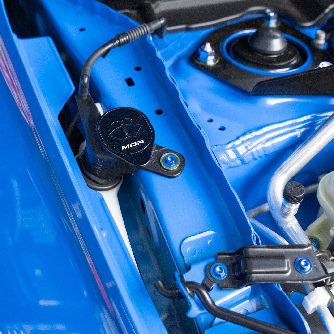 Close-up of a blue vehicle's engine compartment with visible titanium bolts