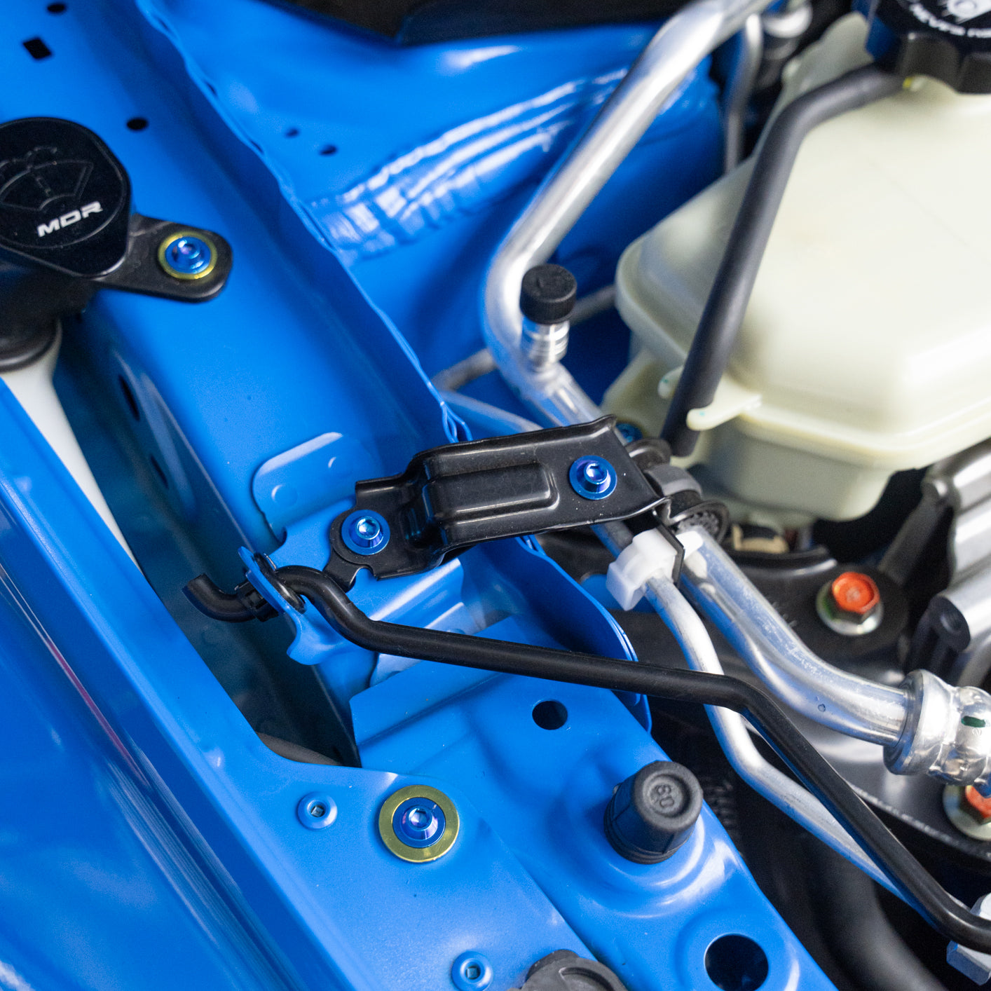 Close-up of a blue car's engine and titanium hardware