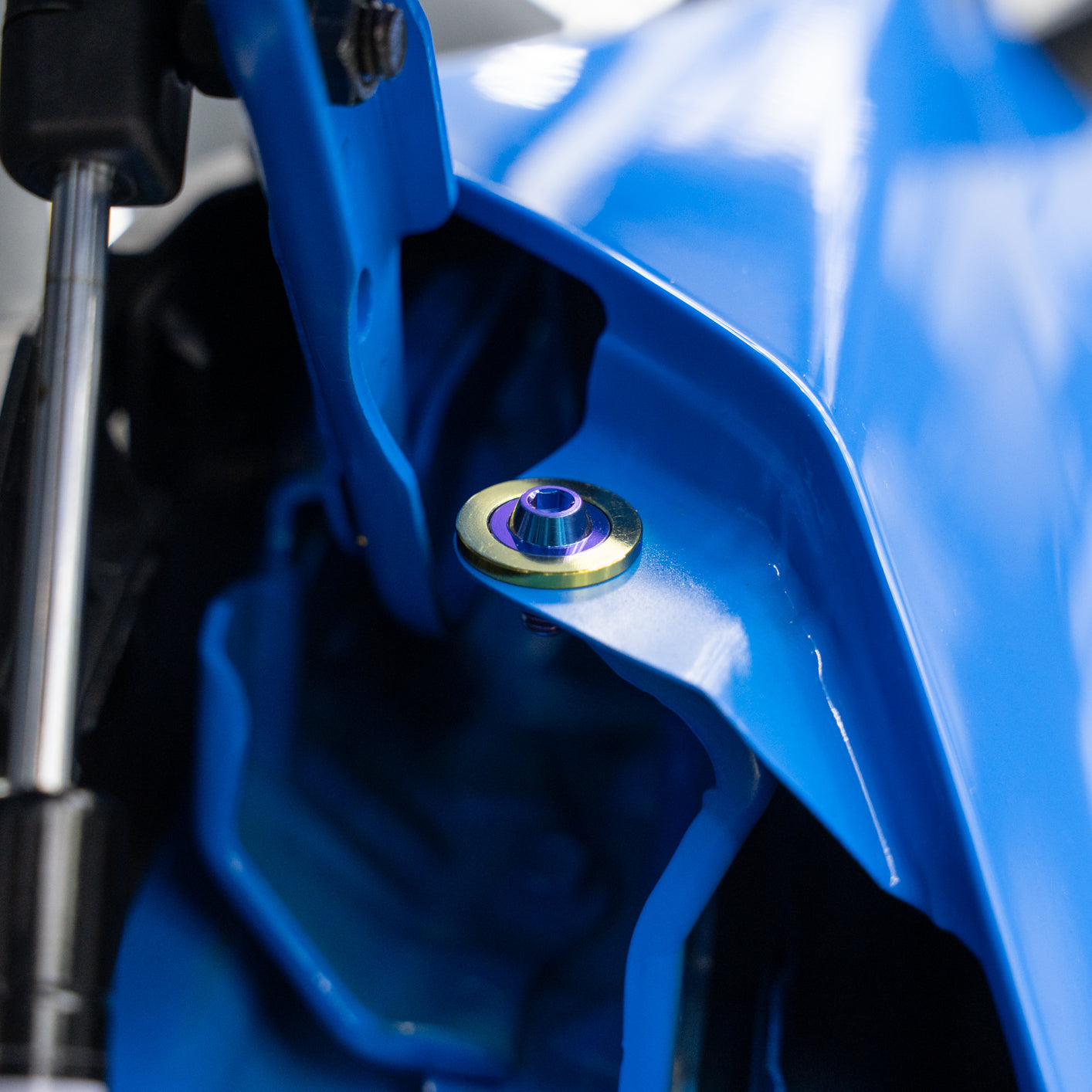 Close-up of a blue car with a shiny titanium screw.