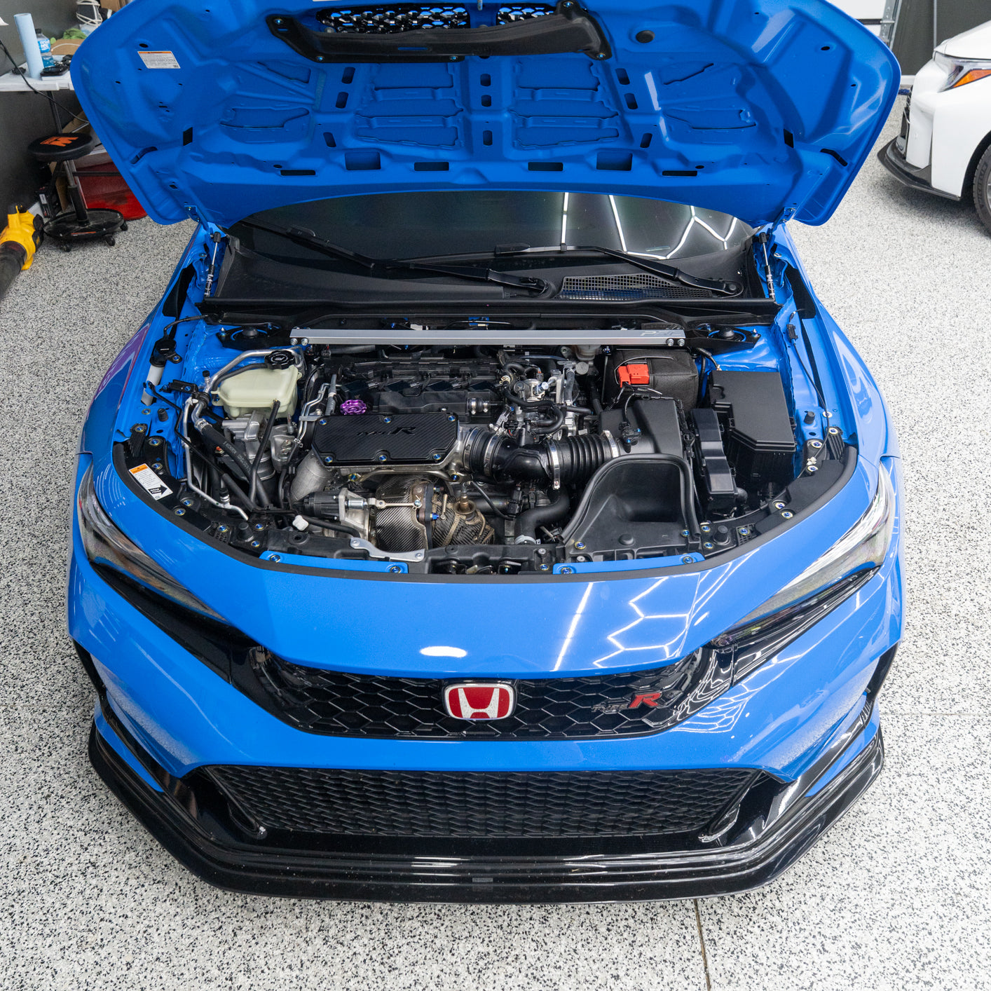 Blue Honda car with open hood in a garage showing off it titanium engine bay hardware