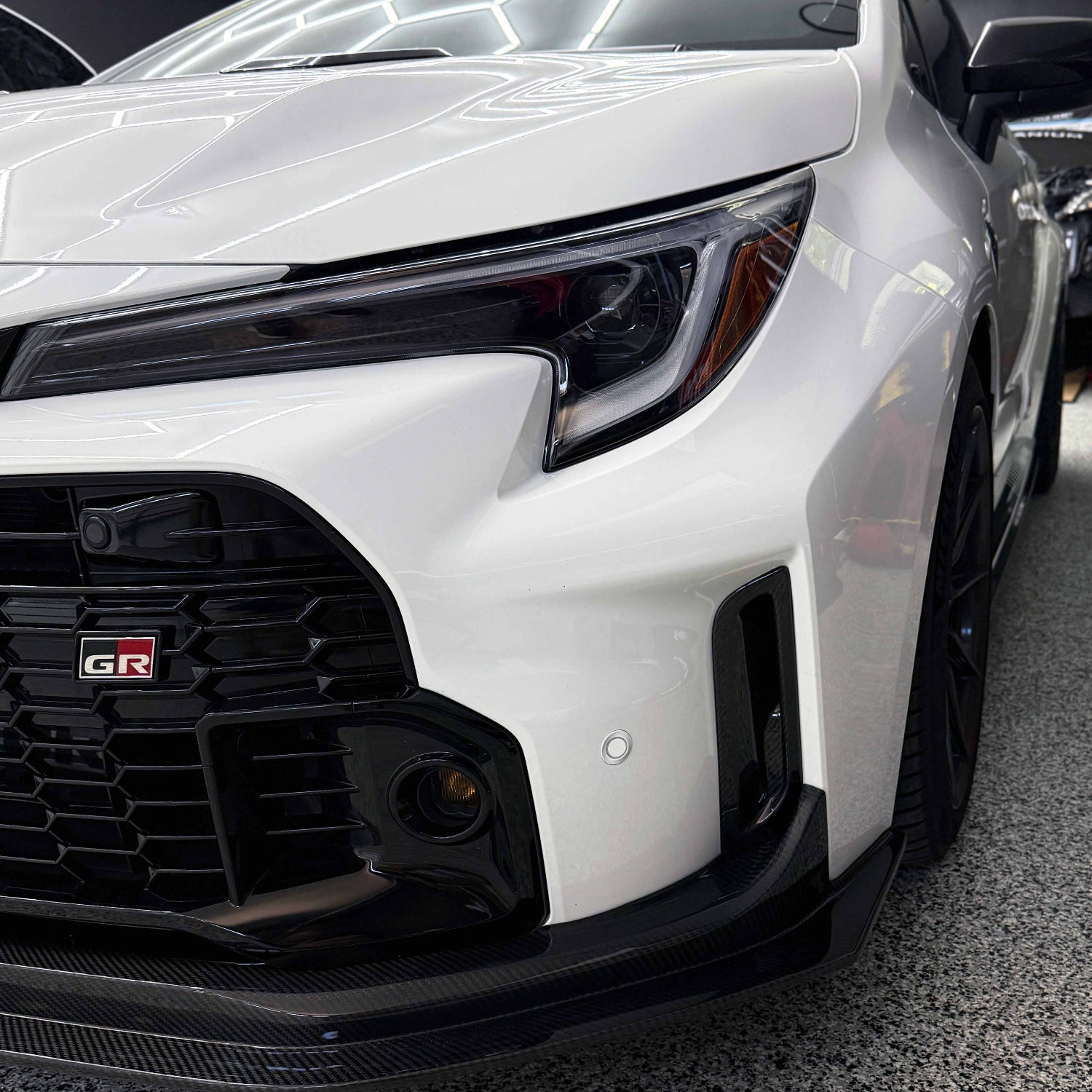 Close-up of a white Toyota GR Corolla front bumper air ducts.