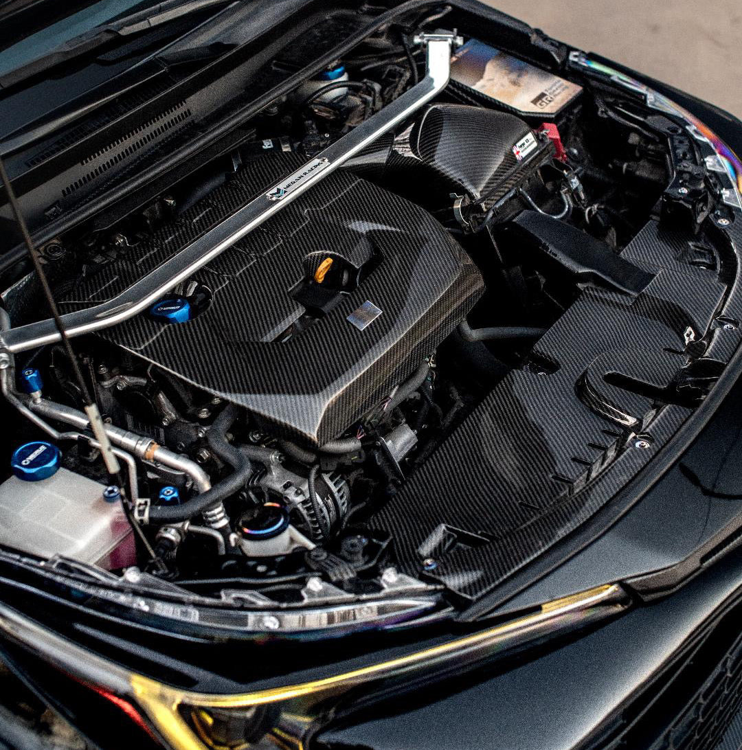 Car engine compartment with open hood displaying jdc titanium hardware, washer fluid cap, and fuse box cover.