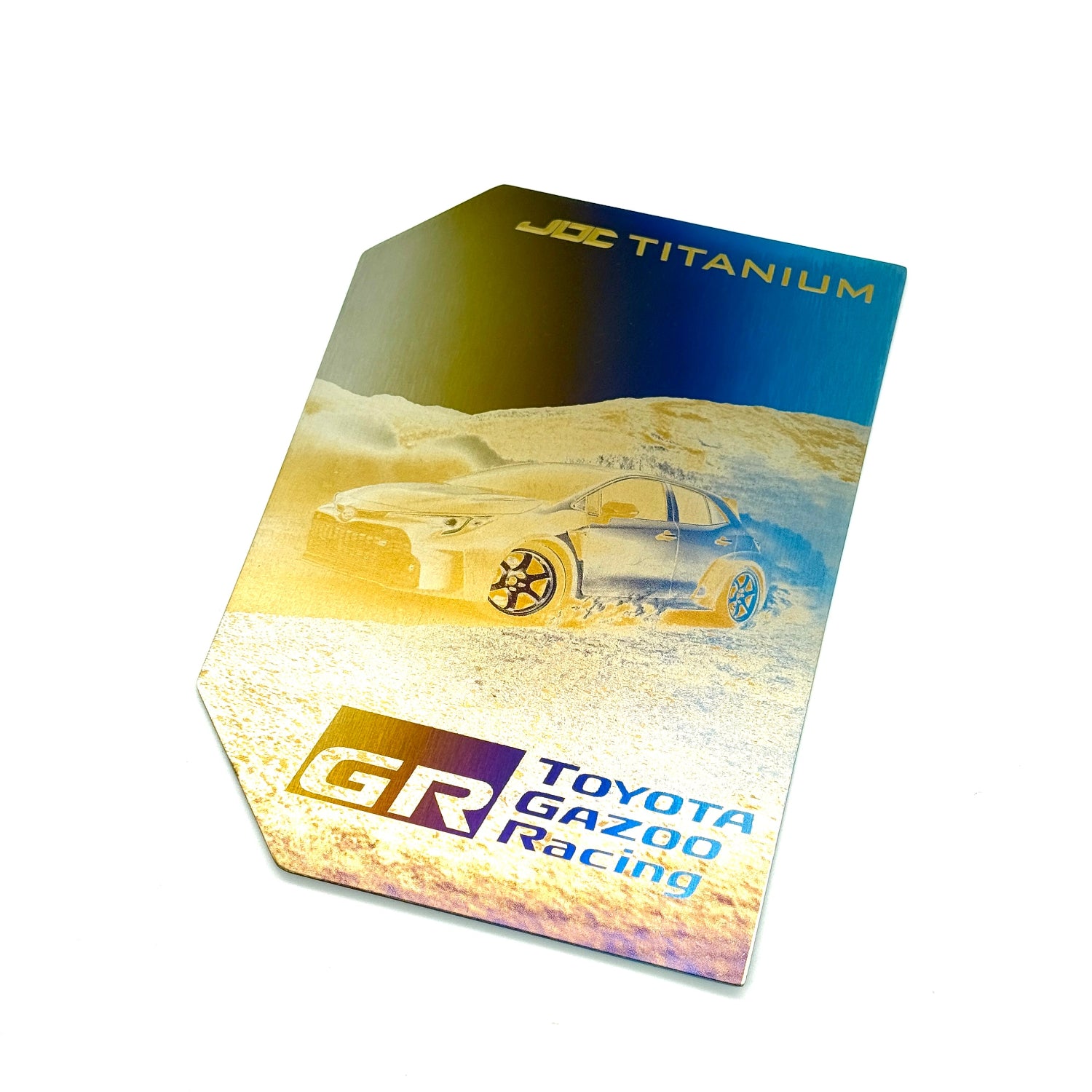 Toyota Gazoo Racing logo laser-etched on a titanium fuse box cover and JDC Titanium branding on a desert landscape background.