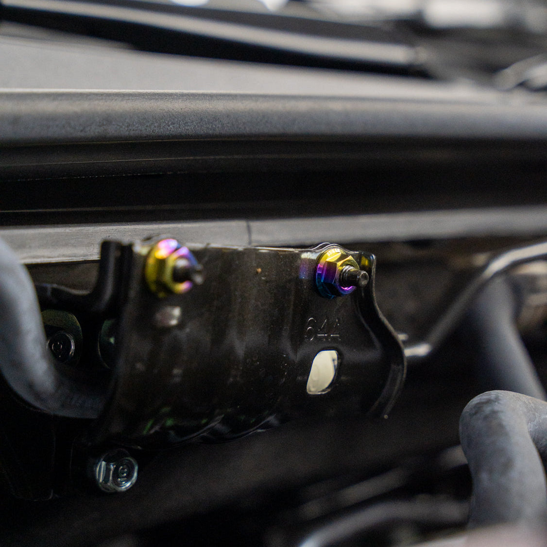 Gradient freaktanium titanium hardware installed on a white Acura Integra A-Spec hood latch
