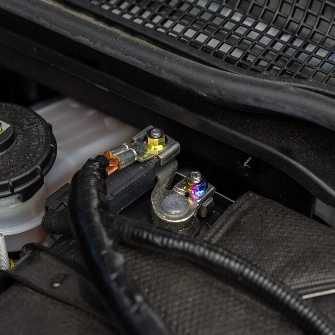 Gradient freaktanium titanium hardware installed on a white Acura Integra A-Spec battery