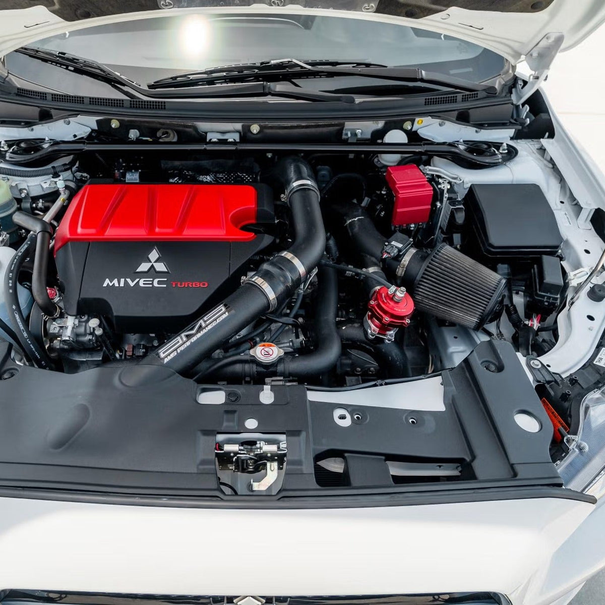 Mitsubishi Evolution X stock engine bay displaying a factory fusible link box with a red cover