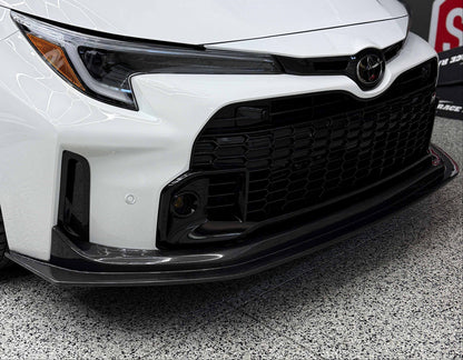 Rexpeed carbon fiber V1 front splitter for 2023-2024 Toyota GR Corolla installed on a white car.