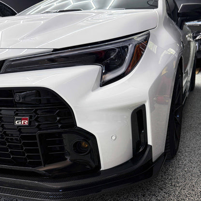 Close-up of a white Toyota GR Corolla front bumper air ducts.