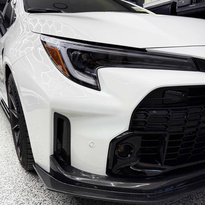 Close-up of a white Toyota GR Corolla front bumper air ducts.