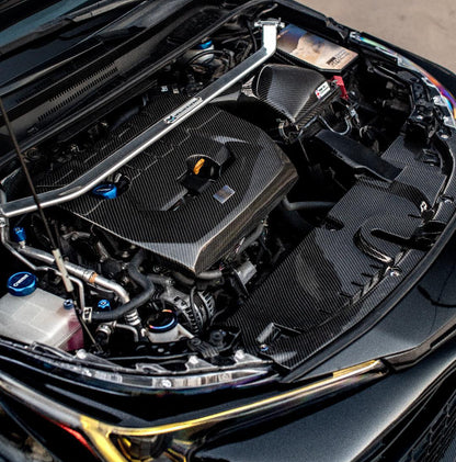 Car engine compartment with open hood displaying jdc titanium hardware, washer fluid cap, and fuse box cover. 