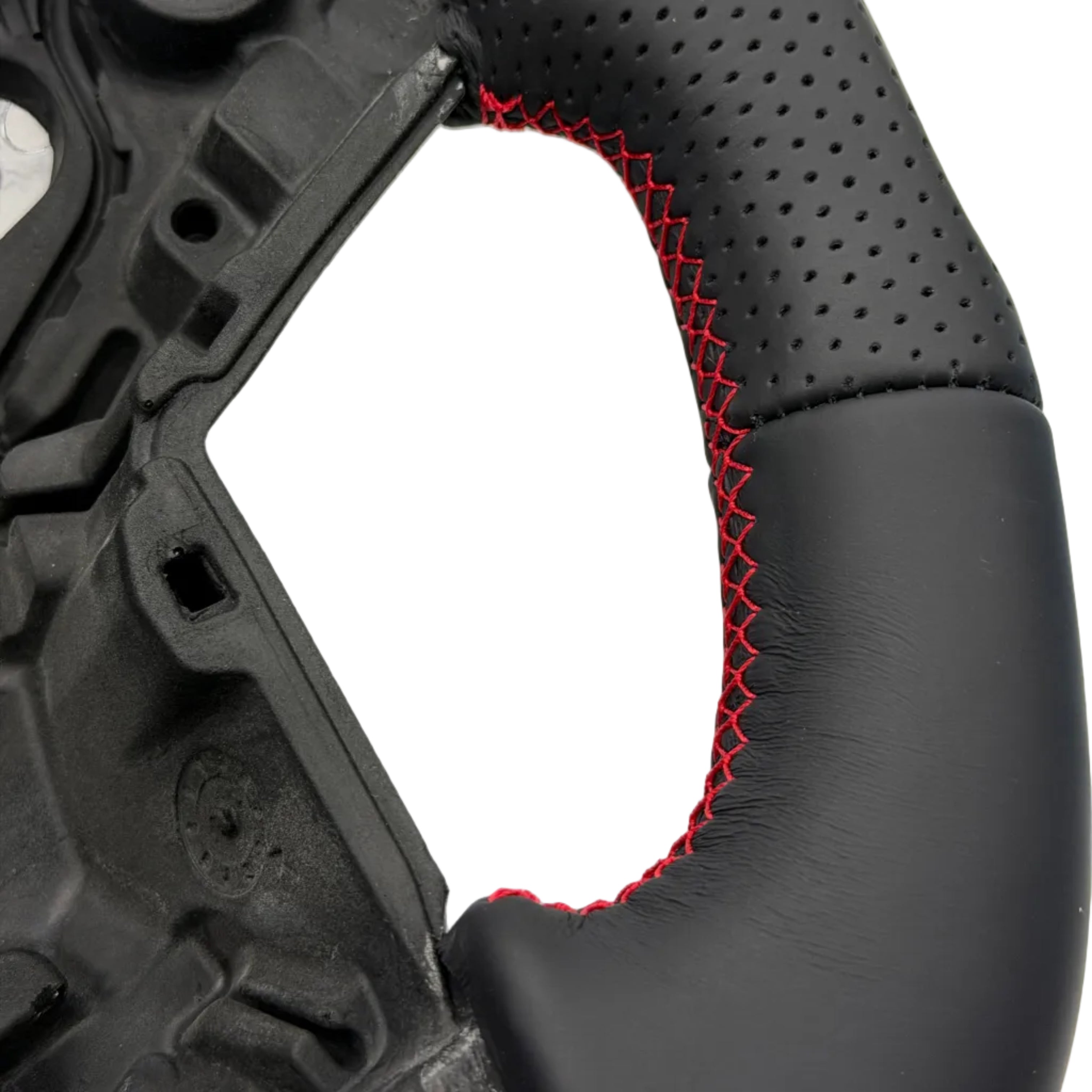 Close-up of a black perforated and leather-wrapped steering wheel rim with red contrast stitching along the inner edge, shown against a white background.