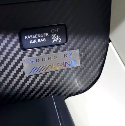 Car interior with a passenger airbag indicator and an Alpine sound system badge.
