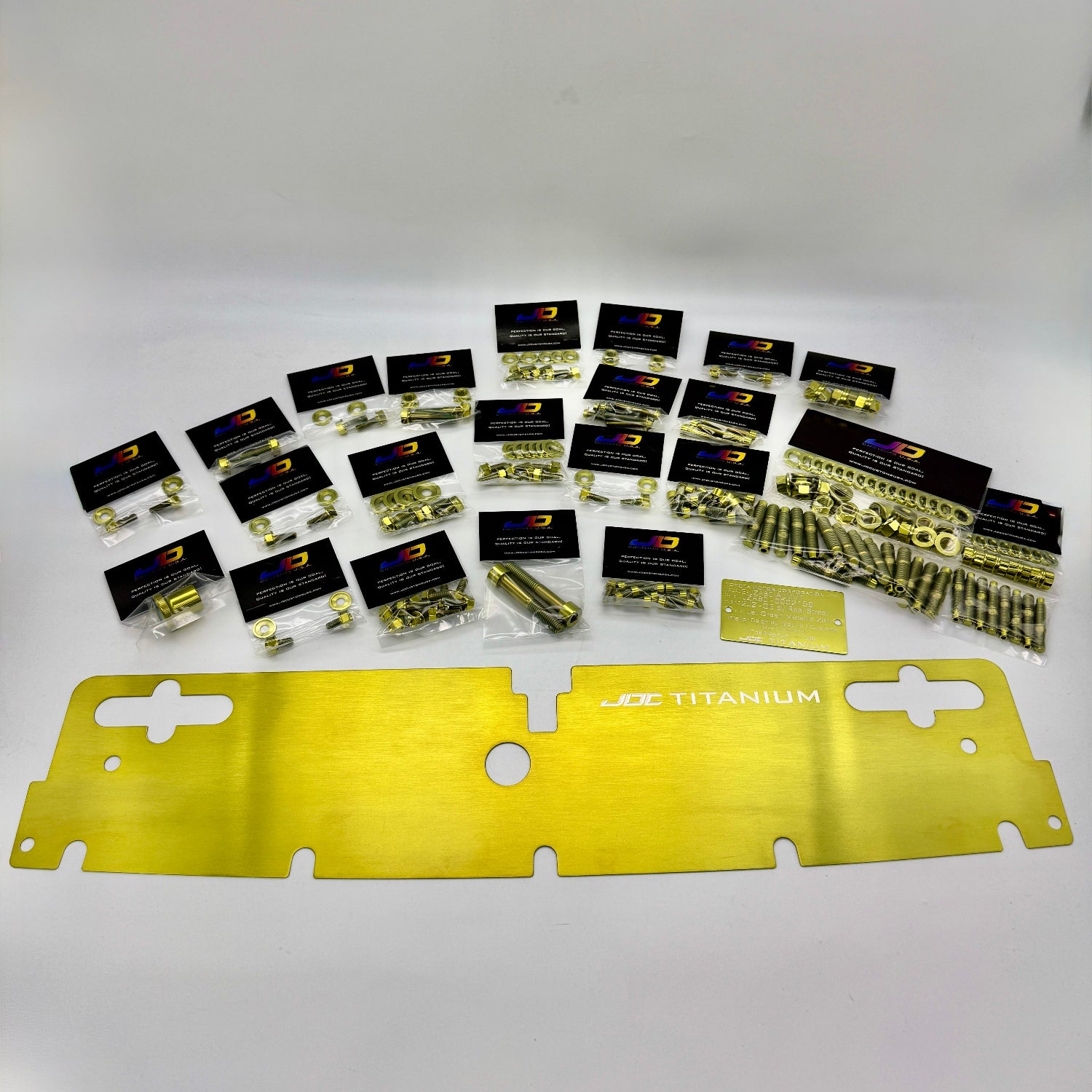 Collection of JDC titanium hardware packages on a white surface with a gold titanium radiator cooling plate.