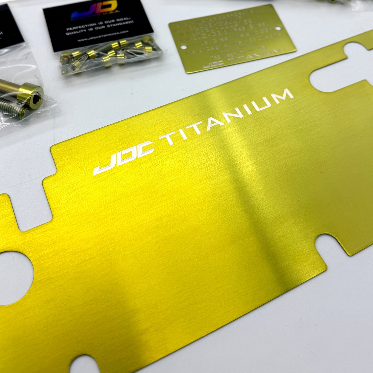 JDC titanium hardware packages on a white surface with a gold titanium radiator cooling plate.
