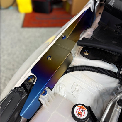 JDC Titanium fender shroud for 2023-2025 Toyota GR Corolla in a burnt gradient finish with matching titanium hardware installed on a white GR Corolla.