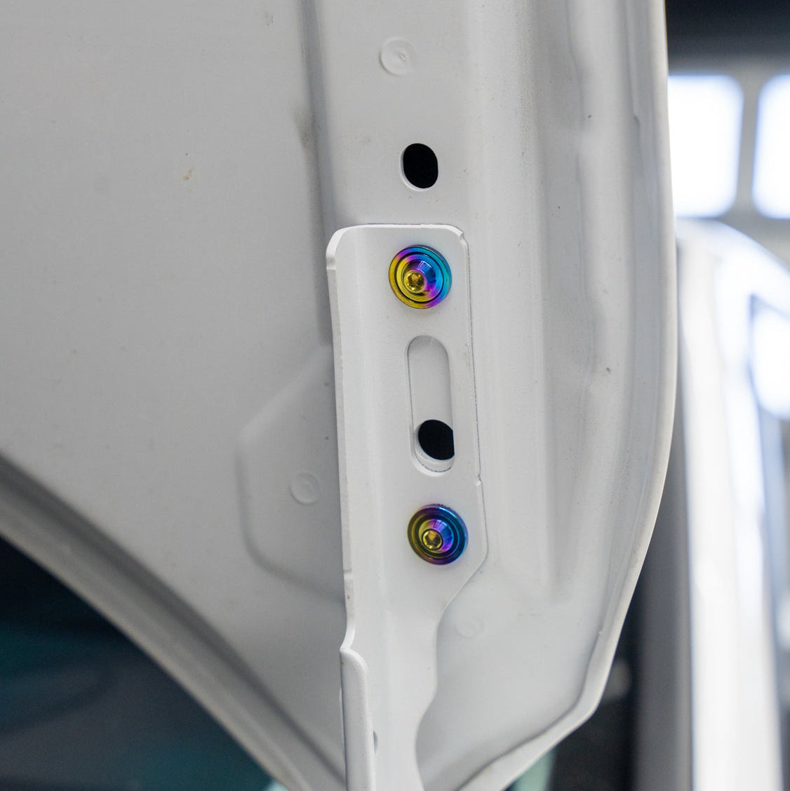 Gradient freaktanium titanium hardware installed on a white Acura Integra A-Spec hood bracket