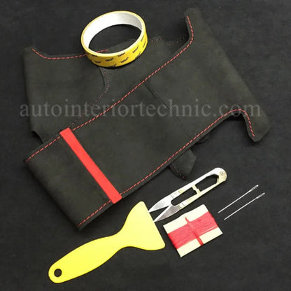 Black leather car dashboard cover with red stitching, measuring tape, knife, and scraper on a black background.