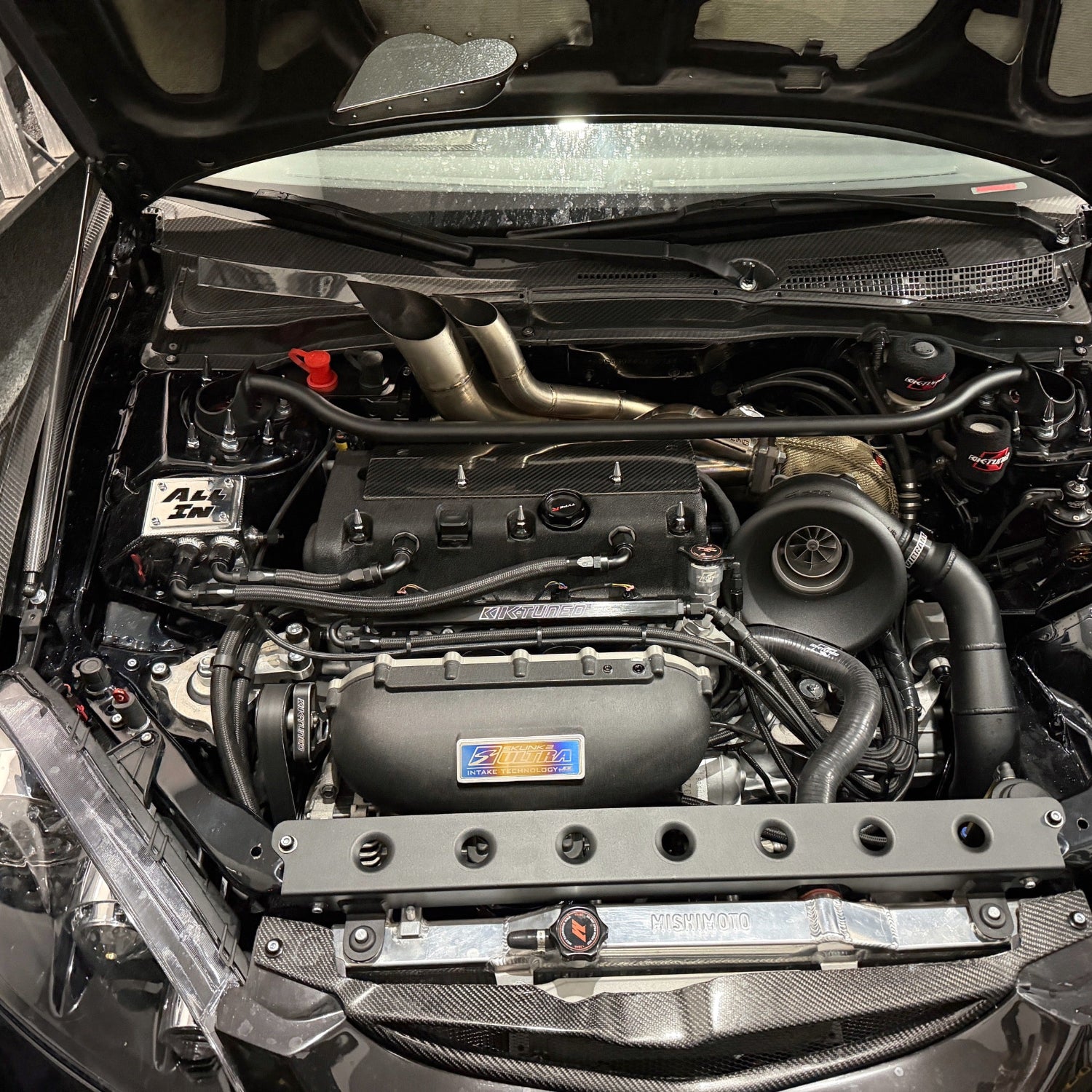 Car engine compartment with visible Skunk2 badge branding JDC titanium badge